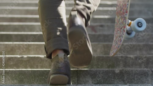 Man Walking up the stairs outdoor with backpack holding skateboard long lens afternoon beautiful natural surrounding slow motion