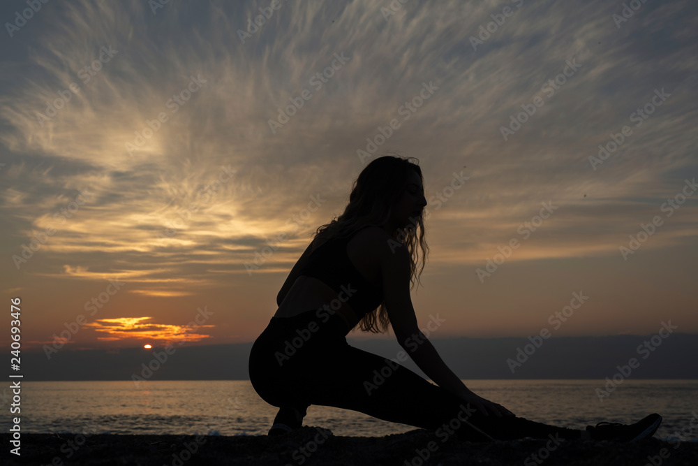 young woman does exercise at sunrise