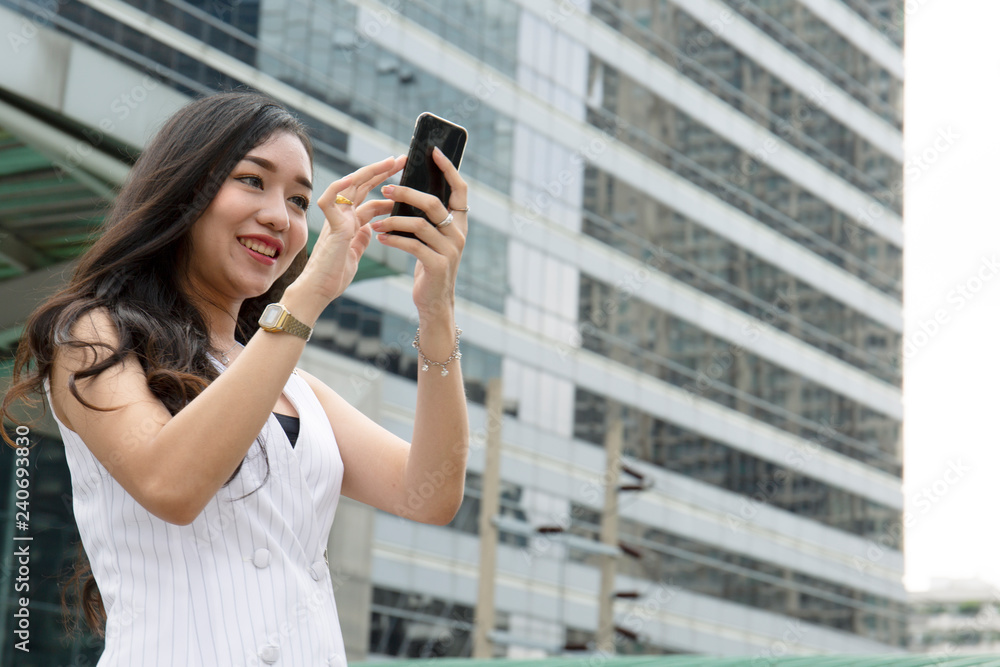 Beautiful woman playing mobile phone device and office building background. Beautiful woman playing mobile phone device and office building background.