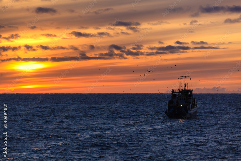 sunrise with clouds on the ocean with a fishing boat