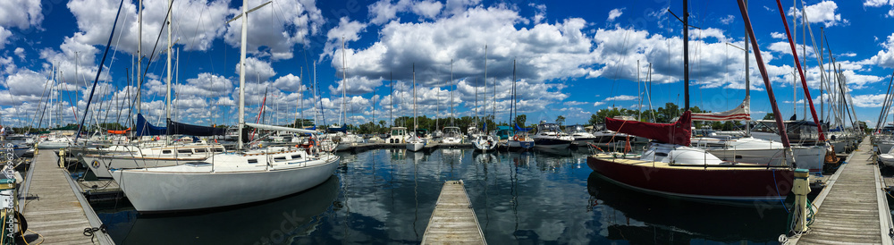 Large sailboats tied up at dock in yacht club in summer with beautiful, blue cloudy sky, panorama