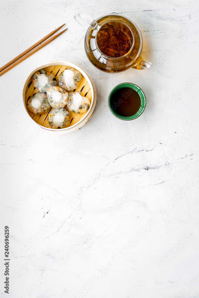 Chinese steamed dumplings Dim Sum in bamboo steamer with tea on marble background top view mock up Chinese steamed dumplings Dim Sum in bamboo steamer with tea on marble background top view mock up