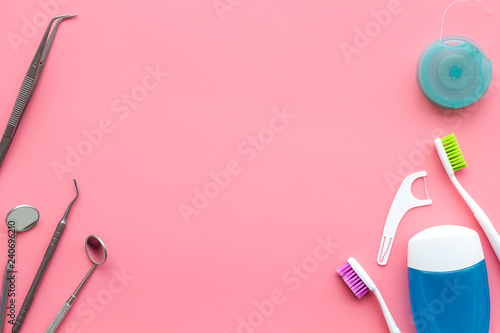 Tooth care with toothbrush, dental floss and dentist instruments. Set of cleaning products for teeth on pink background top view copy space