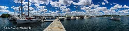 Large sailboats tied up at dock in yacht club in summer with beautiful, blue cloudy sky, panorama © Vito