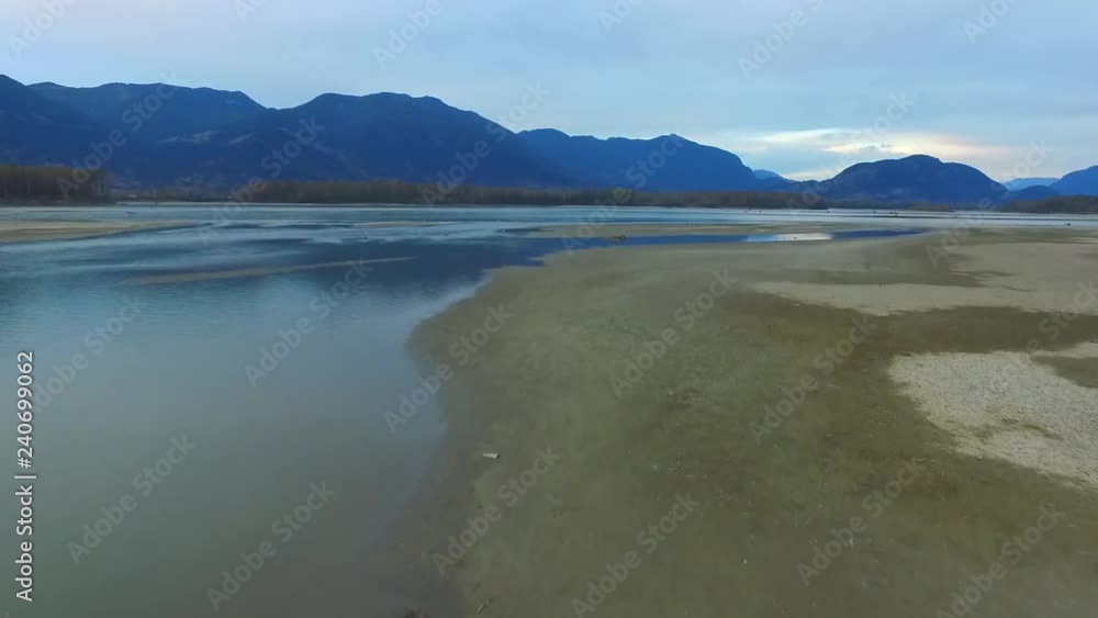 low angle aerial dolly of drying up river bed with large mountains in the distance low angle aerial dolly of drying up river bed with large mountains in the distance
