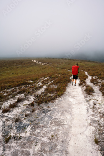 A man hiking on a path with fog in the sky