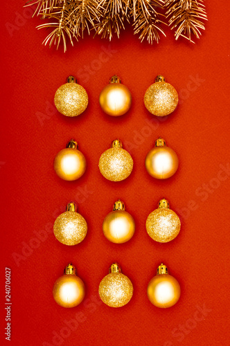 Multiple Christmas gold baubles creative decoration pattern with golden pine tree branches on the red background