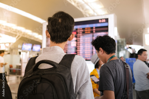 A man with backpacker looking for information on electronic information board and departure board in airport. Royalty stock image of tourist in terminal departure find for information on departure