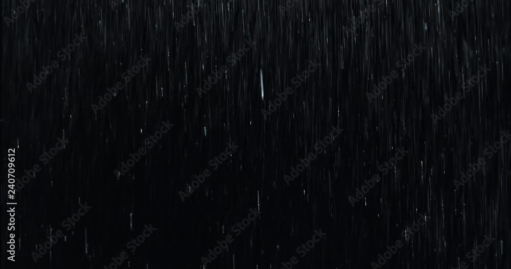 Heavy rain wall falling in front of the camera against black screen. Raindrops splashing. Rain closeup vfx insert. Practical seamlessly loopable footage. Heavy rainstorm hitting black surface.