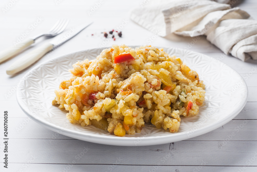 Pilaf with vegetables and chicken in a gray plate on a light background. Pilaf with vegetables and chicken in a gray plate on a light background.