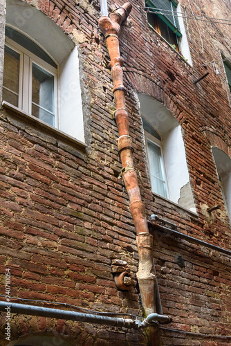 Medieval clay downspout on street Vicolo degli Orefici in Siena, Tuscany, Italy photo