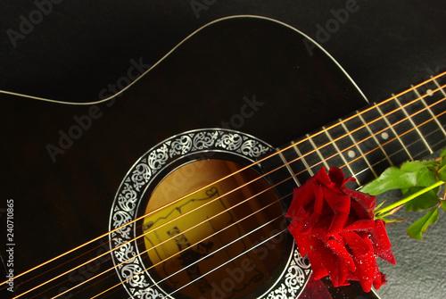 Acoustic black guitar and red rose. 