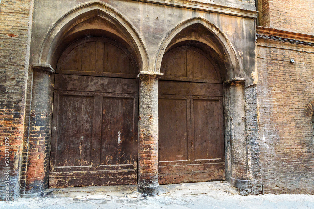 Wooden arch door on medieval brick building in Siena. Italy