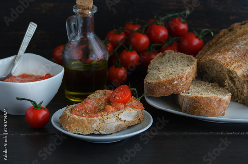 Popular Spanish breakfast. Crusty bread with fresh cherry tomato and olive oil is typical tapa  in Spain, especially in Catalonia photo