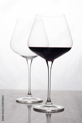 two glass glasses empty and with red wine on a white background.