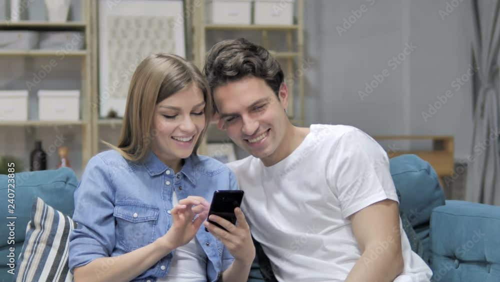 Happy Young Couple Browsing Internet on Smartphone at Home Happy Young Couple Browsing Internet on Smartphone at Home
