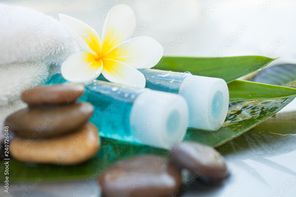 Spa or wellness setting with tropical flowers and small bottle with oil. Body care and spa concept Spa or wellness setting with tropical flowers and small bottle with oil. Body care and spa concept