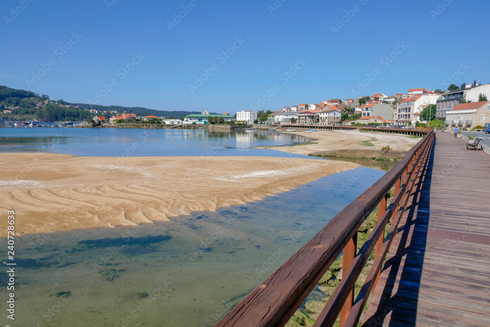 Playa gallega de Aldán con paseo de madera en día de sol