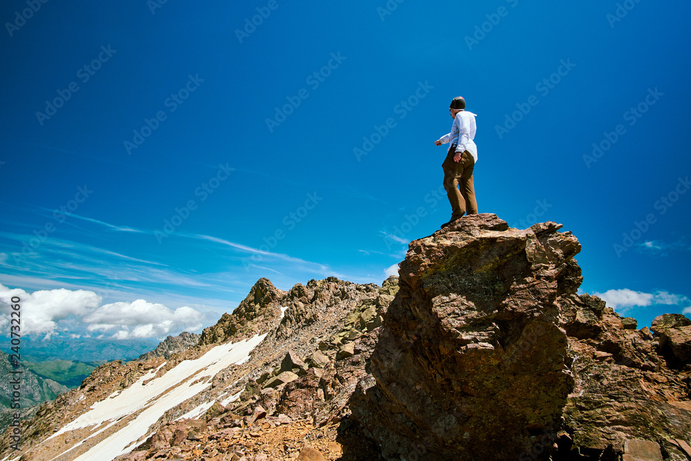 A tourist boy pointing at the top of Monte Cinto near the snow field in Corsica on sunny day GR20