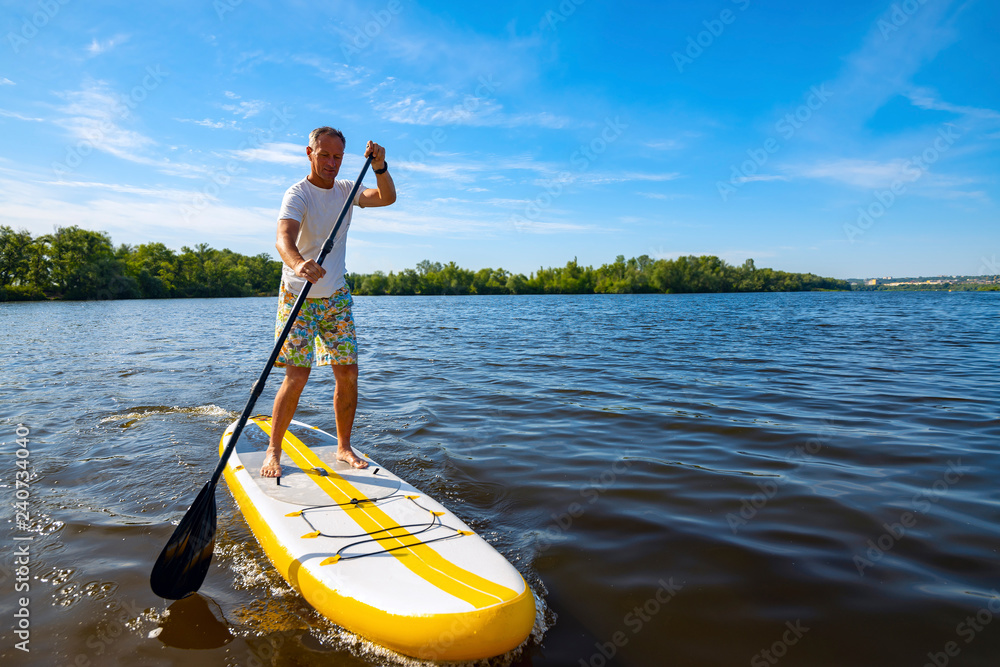 Happy man is paddling on a SUP board