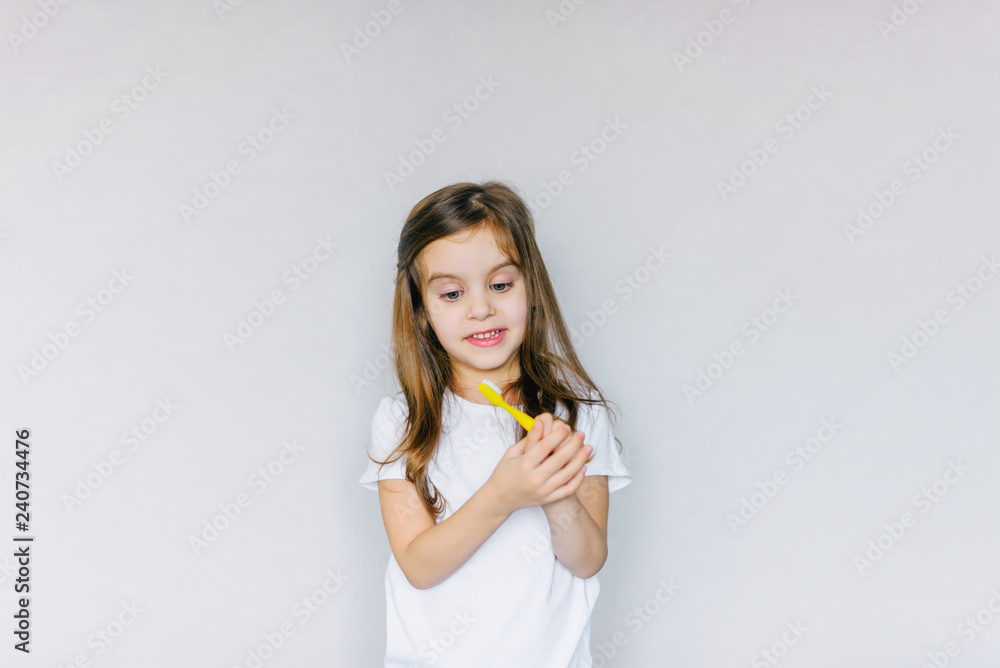 Little cute baby girl with toothbrush and tooth layout in hand. The concept of health, oral hygiene, people and beauty. The layout of the space. Selective focus. Little cute baby girl with toothbrush and tooth layout in hand. The concept of health, oral hygiene, people and beauty. The layout of the space. Selective focus.