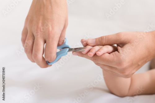 Mother cutting baby finger nails with scissors