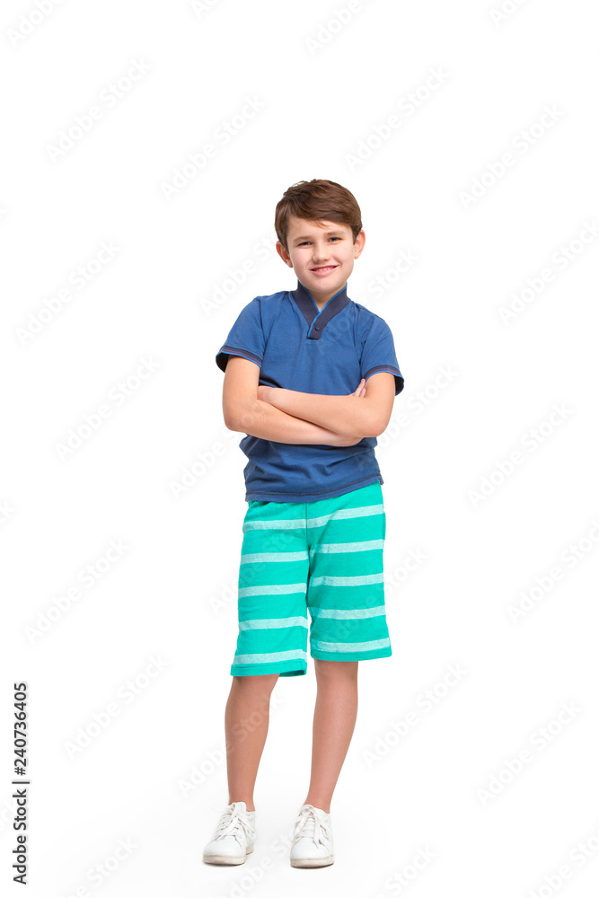 Full length portrait of cute little kid boy in stylish clothes looking at camera and smiling, standing against white studio wall. Kids fashion concept Full length portrait of cute little kid boy in stylish clothes looking at camera and smiling, standing against white studio wall. Kids fashion concept