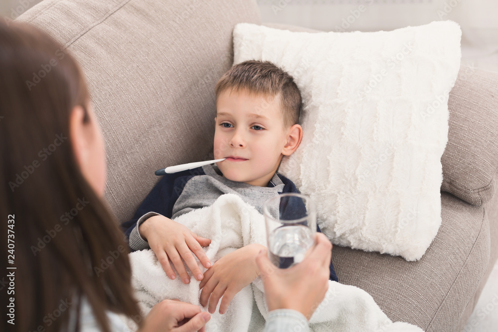 Little boy measuring temperature with thermometer on sofa Little boy measuring temperature with thermometer on sofa
