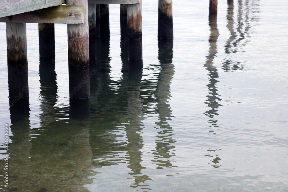 Coastal harbor with wooden pier dock on sandy rocky beach Coastal harbor with wooden pier dock on sandy rocky beach
