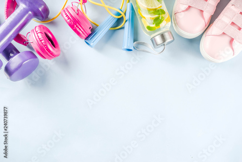 Sport and fitness creative layout, dumbbells, women's sneakers, jump rope, notebook, bottle with detox water with lemon and mint, bright trendy background, top view, creative layout copy space