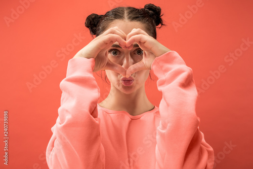 I kiss you ands love you. Portrait of attractive woman with kiss on lips. Coral studio. Beautiful female portrait. Young happy emotional funny woman looking at camera. Human facial emotions concept