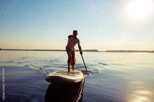 Obraz na płótnie Joyful guy paddling on a SUP board w salonie