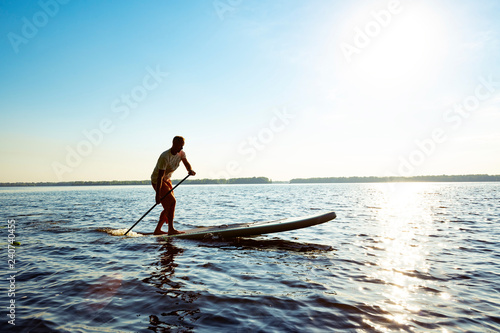 Obraz na płótnie Joyful guy paddling on a SUP board w salonie