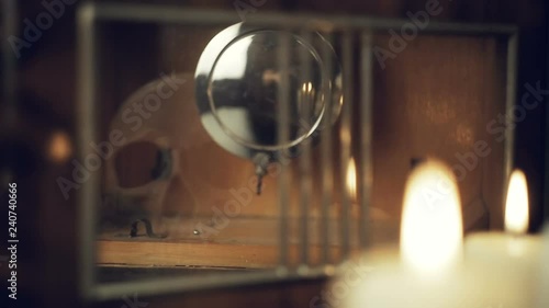 reflection of the skull and candles in the pendulum of an old clock