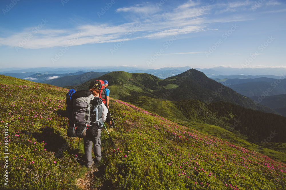 Travelers, friends going up on the mountain trail