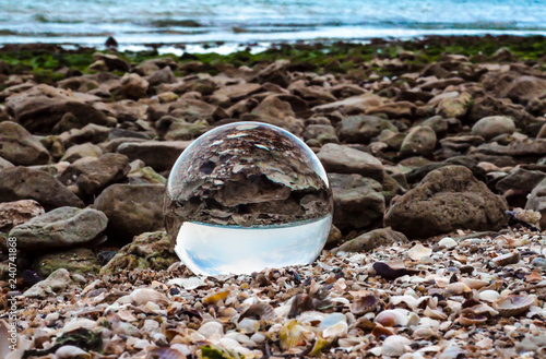 glass ball lens lies on the sand of the sea shore