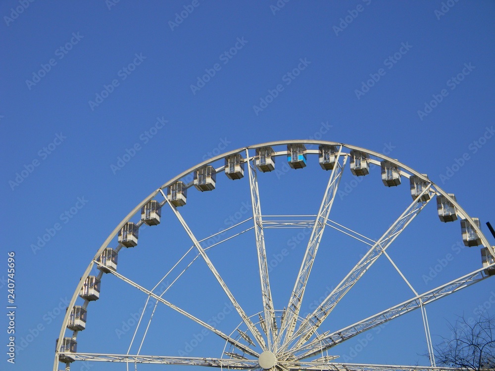 Ferris wheel with empty cabins against sky background Ferris wheel with empty cabins against sky background