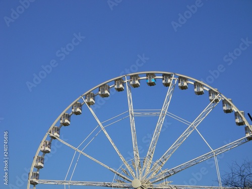 Ferris wheel with empty cabins against sky background