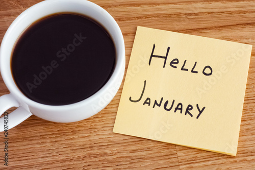 Post it note with writing Hello January and cup of coffee