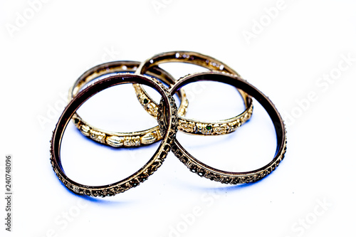 Close up of golden colored metal bangles isolated on white with some diamonds on it.