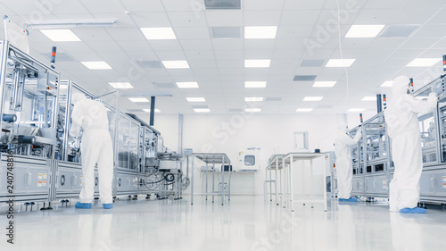фотографія Team of Research Scientists in Sterile Suits Working with Computers, Microscopes and Modern Industrial Machinery in the Laboratory