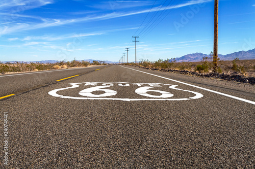 Ground level road view of Route 66 with logo in the Mojave Desert.