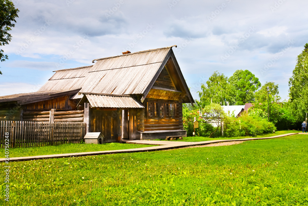 Ancient wooden peasant house and a wooden church on the green grass