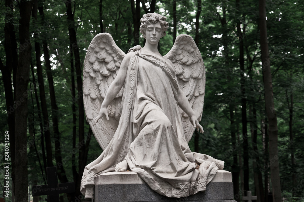 The Sorrowful Angel. Marble mourning angel on a background of green foliage The Sorrowful Angel. Marble mourning angel on a background of green foliage