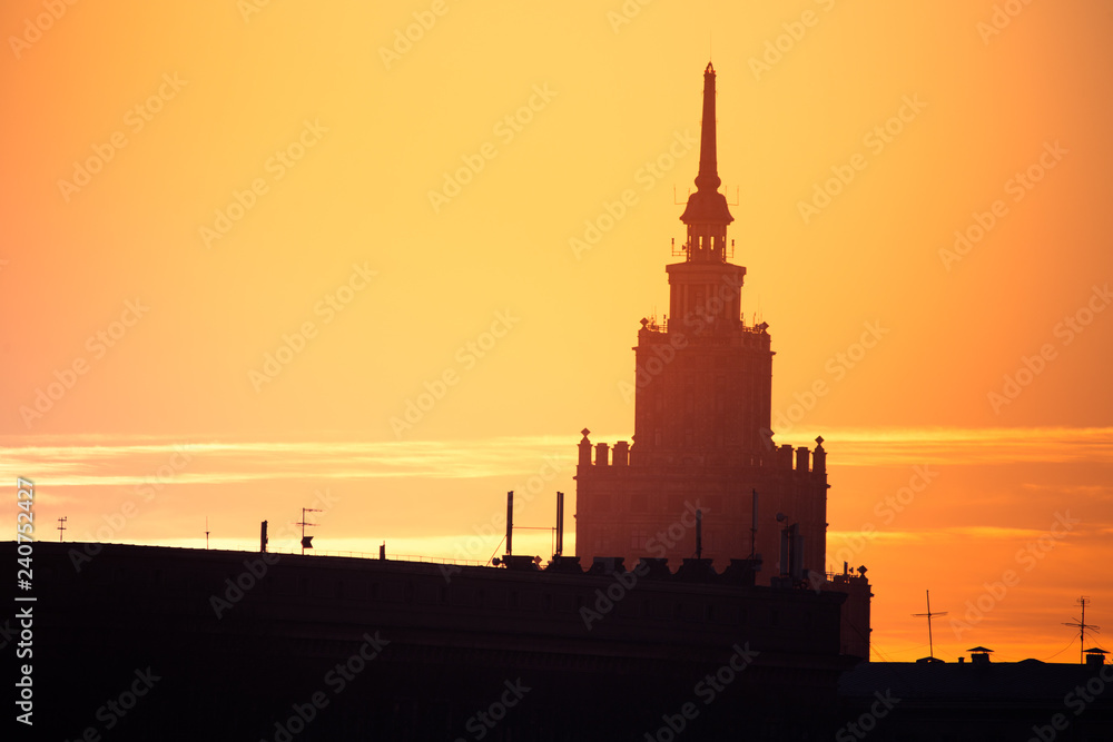 A beautiful silhouette of a tower in city during the sunrise. Morning scenery of Riga, Latvia. Tall building in city. Colorful cityscape.