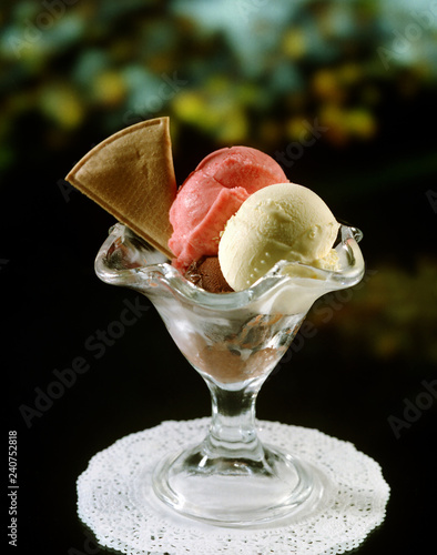 Copa de helado con tres bolas, vainilla, fresa y chocolate y una galleta de adorno.