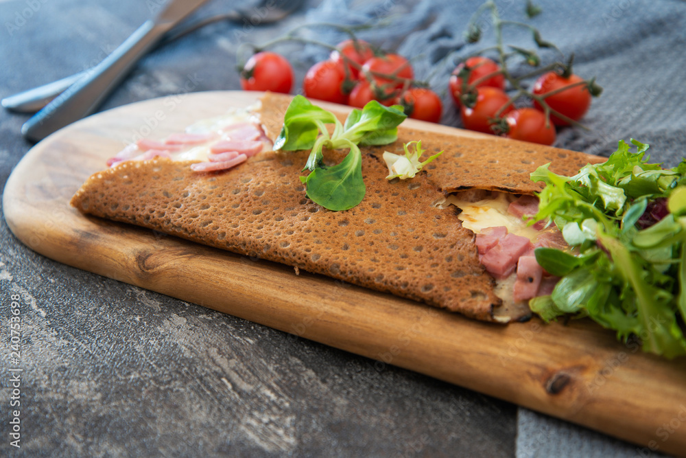 Black wheat and wheat galette topped with cooked ham and emmental cheese Black wheat and wheat galette topped with cooked ham and emmental cheese