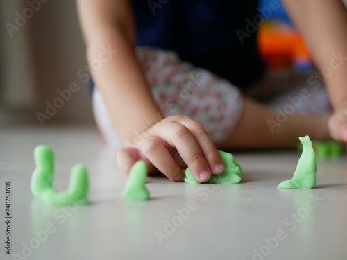 Little baby's hand playing playdough on the house floor - playing dough promotes baby's creativity, imagination, and fine motor skill development