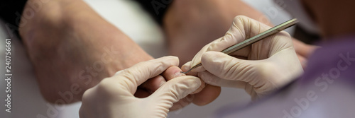 Closeup view of pedicurist removing dead skin from toenails photo