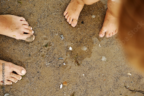 Mother's and doughter's feet on the wet sand. Summer family vacation.